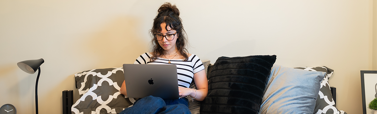 Tenant sitting on their bed with laptop