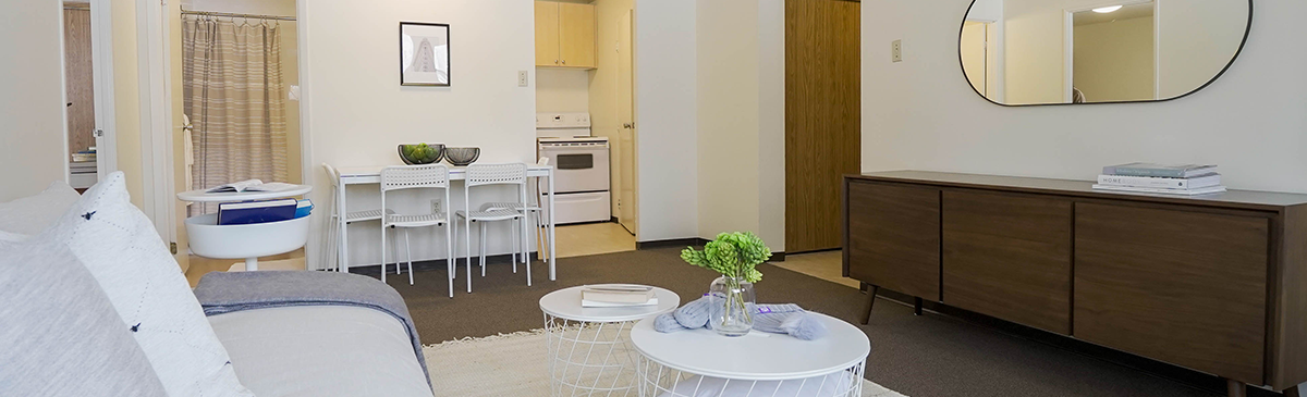 Living room showing couch, coffee table, cabinet and looking at kitchen
